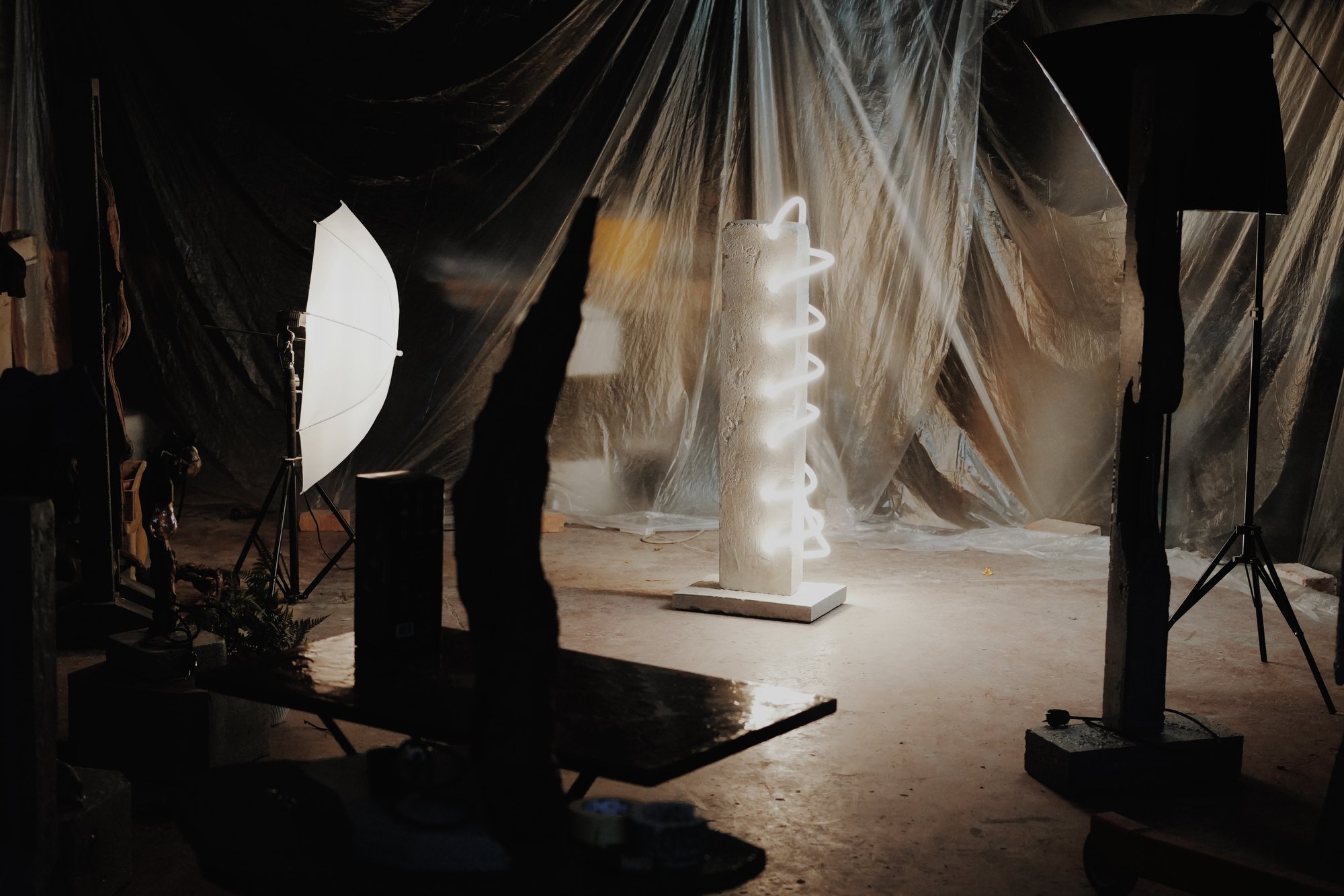 Il laboratorio durante uno shooting: la lampada Intreccio accesa tra teli di plastica, luci da studio e altri pezzi in ombra